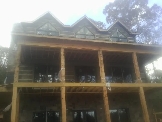 Dormers and porch framing on a large log home under construction — Roof Coating work by our crew in Peekskill