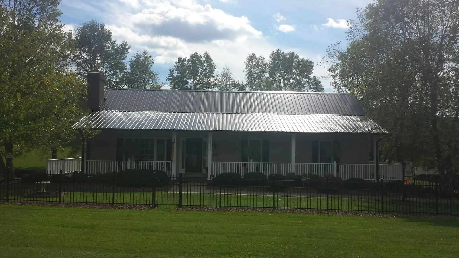 Gray metal roof on a brick ranch with a full width front porch — Gutter Guard Installation work by our crew in Peekskill